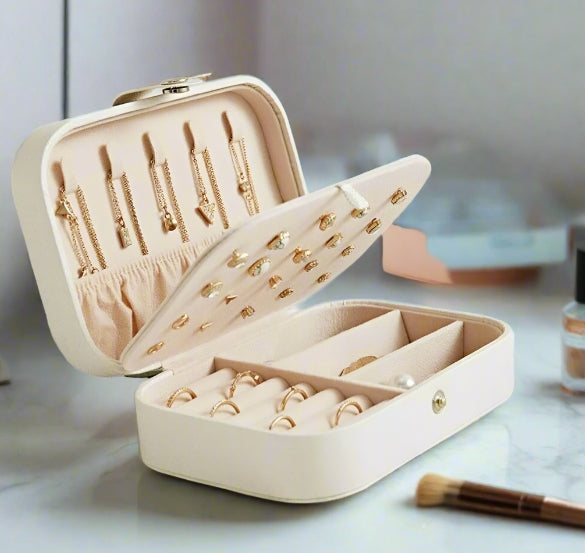 Beige jewelry box with gold jewelry on a light surface