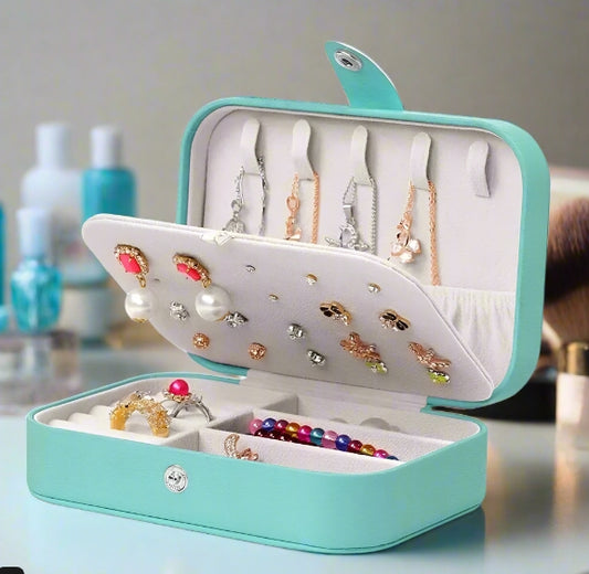 Turquoise jewelry box with earrings and necklaces on a neutral background