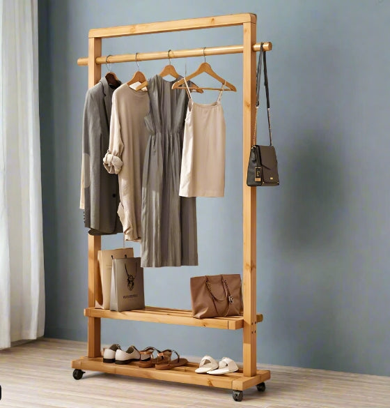 Wooden clothing rack with clothes and bags against a gray wall.