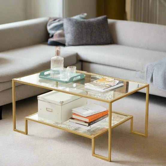 Gold-framed glass coffee table with two-tier tempered glass shelves in a modern living room setting

