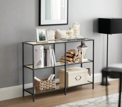Modern 3-tier black steel console table with clear tempered glass shelves in stylish living room


